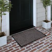 Designer Welcome Entry Doormat Placed on Solid Brick Floor Outside Entry Door with Plants photo