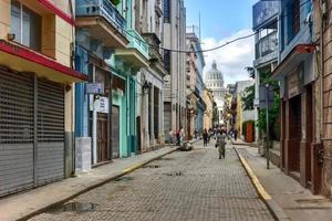 la habana, cuba - 8 de enero de 2017 - gente caminando por las calles de la habana vieja con el edificio de la capital nacional al fondo. foto