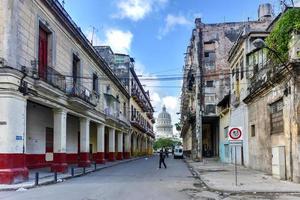 la habana, cuba - 8 de enero de 2017 - gente caminando por las calles de la habana vieja con el edificio de la capital nacional al fondo. foto