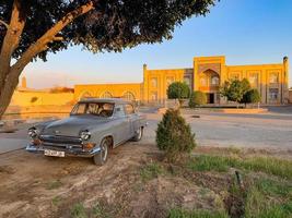 khiva, uzbekistán - 14 de julio de 2019 - coche clásico soviético volga - estacionado fuera de las murallas de la ciudad del sitio de la unesco de khiva, uzbekistán. foto