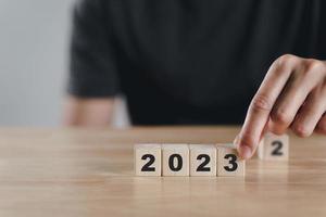 Man hand putting wooden cube block to change 2022 year to 2023 year. start to year 2023. happy new years concept. photo