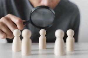 Hand Holding A Magnifying Glass Focusing On Wooden Figure .job search, human resources, hiring Concept photo