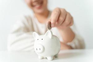 Close up of woman hand putting money coin into piggy bank for saving money. saving money and financial concept photo