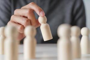 Man hand chooses wooden peg doll. leadership and business team creative thinking and human resources for teamwork or team player concept. photo