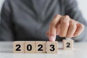 Man hand putting wooden cube block to change 2022 year to 2023 year. start to year 2023. happy new years concept. photo