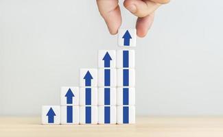 Growth, increase of business and economy concept. Human hand placing a cube with up arrow on top of other stacked blocks. Copy space photo