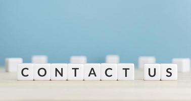 Contact us message on cube blocks on wood table. Copy space. Blue background photo