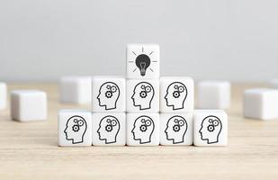 Team Brainstorming, creative idea or innovative idea concept. Cube blocks with gear head icon arranged in pyramid stair shape and a light bulb icon on top photo