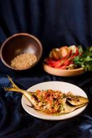 pescado frito con chile rojo en un plato blanco. parte de la comida padang foto