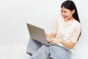 joven mujer asiática alegre sentada y usando una computadora portátil. tecnología y concepto de aprendizaje. foto