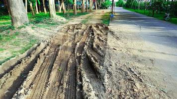 Cartire tracks on dark brown dirt road caused by rain water photo