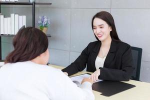 Asian professional woman is working and pointing confident on the paper or document to discuss with her boss at office. photo