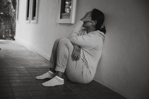 Schizophrenia with lonely and sad in mental health depression concept. Depressed woman sitting against floor at home with dark room feeling miserable. Women are depressed, fearful and unhappy. photo