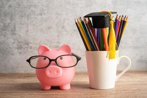 Pigging bank wearing eyeglass with colorful pencils photo