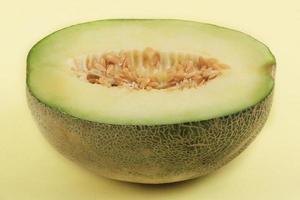 A piece of melon on a yellow pedestal surface photo