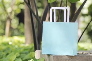 Light blue single paper bag on cement surface in garden. Unbranded paper bag used for mockup photo