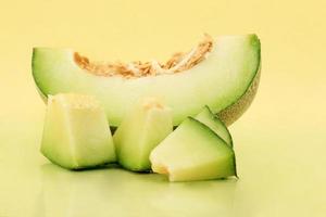 Slices and pieces of melon on the surface of a minimalist yellow base photo