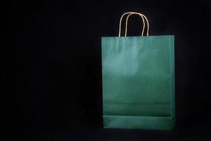 Plain green paper bag packaging on a black background with copy space photo