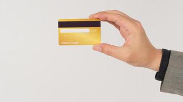 A hand is holding back of gold credit cards and wearing a suit on white background. photo