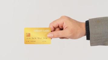 la mano sostiene una tarjeta de crédito dorada y lleva traje de fondo blanco. foto
