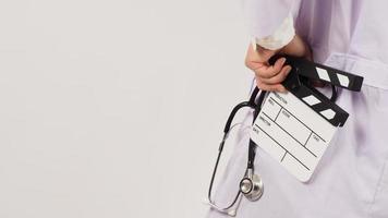 Clapper board and stethoscope in doctor's hand on white background. Studio shooting. photo