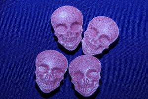 Pink skull ecstasy pill close up background high quality print purple army dope narcotics substance high dose psychedelic way of life photo