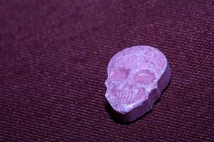 Pink skull ecstasy pill close up background high quality print purple army dope narcotics substance high dose psychedelic way of life photo