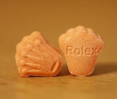 Orange pills with mdma ecstasy dope rolex drug close up background fine art in high quality print photo