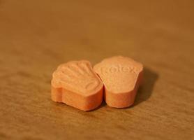 Orange pills with mdma ecstasy dope rolex drug close up background fine art in high quality print photo