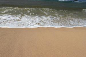 Water foam with smooth sand. Waves on shore of tropical beautiful sand beach on a sunny day photo