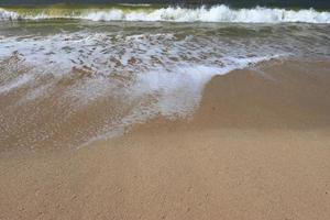 Water foam with smooth sand. Waves on shore of tropical beautiful sand beach on a sunny day photo