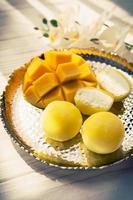 sabroso postre mochi con fruta de mango sobre fondo de madera foto
