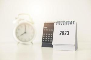 Calendario comercial 2023 y despertador en la mesa de la oficina en el día de año nuevo. hacer un plan de trabajo para el inicio del año. concepto sobre celebración, negocios, navidad, año nuevo. foto