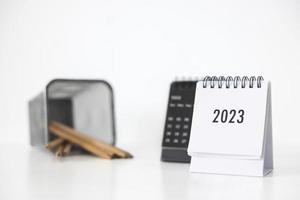 Calendario comercial 2023 y lápiz en la mesa de la oficina en el día de año nuevo. hacer un plan de trabajo para el inicio del año. concepto sobre celebración, negocios, navidad, año nuevo. foto