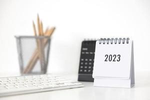 Calendario comercial 2023, teclado y lápiz en la mesa de la oficina en el día de año nuevo. hacer un plan de trabajo para el inicio del año. concepto sobre celebración, negocios, navidad, año nuevo. foto