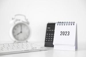 Calendario de negocios 2023, teclado y reloj en la mesa de la oficina en el día de año nuevo. hacer un plan de trabajo para el inicio del año. concepto sobre celebración, negocios, navidad, año nuevo. foto