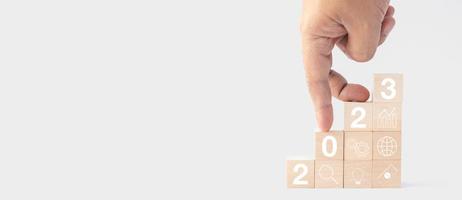 New year 2023 business growing growth concept to success. fingers are walking down woods block step with icon concept about business strategy, Action plan, Goal and target, hand stack, project, vision photo