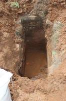 Freshly dug grave pit on the side of the road inside the residence for installation of gas pipes, a close-up. photo