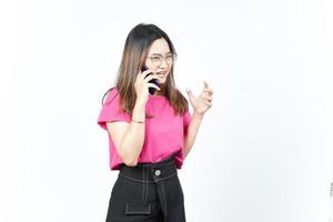 hablando en el teléfono inteligente con la cara enojada de una hermosa mujer asiática aislada de fondo blanco foto