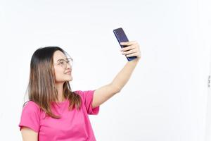 tómate un selfie usando un smartphone de una hermosa mujer asiática aislada de fondo blanco foto