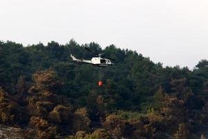 un helicóptero apaga un incendio forestal en las montañas del norte de israel. foto