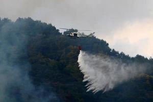 un helicóptero apaga un incendio forestal en las montañas del norte de israel. foto