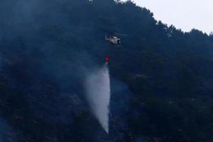 un helicóptero apaga un incendio forestal en las montañas del norte de israel. foto