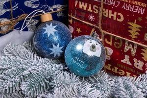 pasatiempo creativo de manualidades. hacer bolas y adornos navideños artesanales hechos a mano con abeto de fieltro. árbol de navidad con bolas de colores y cajas de regalo sobre una pared de ladrillo blanco con bolas azules y blancas foto