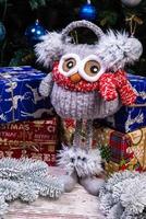 Soft plush toy owl with headphones and knitted scarf. Winter children's gift . Funny knitted red and white toy owl in a red hat and with big eyes