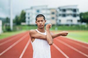 atletas deportistas corredores con ropa deportiva blanca para estirarse y calentarse antes de practicar en una pista de atletismo en un estadio. concepto de deporte de corredor. foto