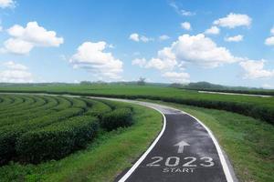 Happy new year 2023,2023 symbolizes the start of the new year. The letter start new year 2023 on the road in the nature fresh green tea farm mountain environment ecology or greenery wallpaper concept. photo