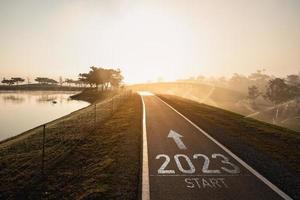 Happy new year 2023,2023 symbolizes the start of the new year. The letter start new year 2023 on the road in the nature route roadway near river in morning sunrise ecology greenery wallpaper concept. photo