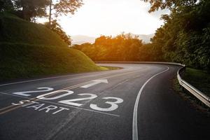 feliz año nuevo 2023,2023 simboliza el comienzo del nuevo año. la carta comienza el nuevo año 2023 en la carretera en la ruta de la naturaleza, la carretera tiene un concepto de ecología del entorno arbóreo o papel tapiz verde. foto
