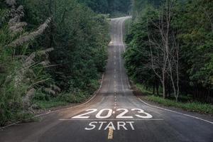 feliz año nuevo 2023,2023 simboliza el comienzo del nuevo año. la carta comienza el nuevo año 2023 en la carretera en la ruta de la naturaleza, la carretera tiene un concepto de ecología del entorno arbóreo o papel tapiz verde. foto